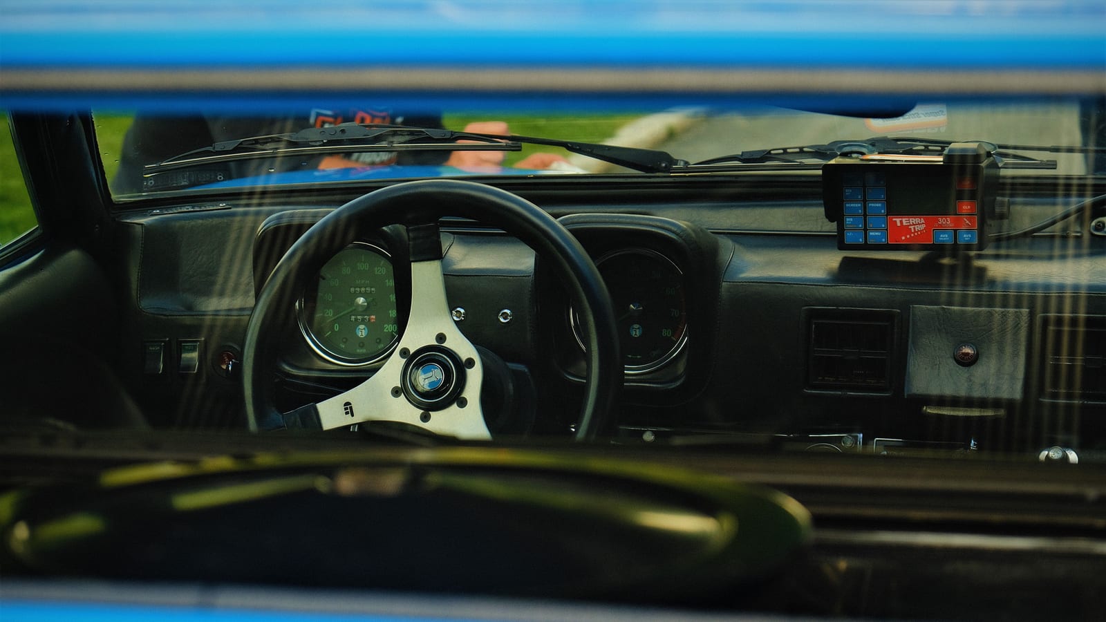 Interior shot of a classic car's steering wheel and dashboard, emphasizing vintage design.