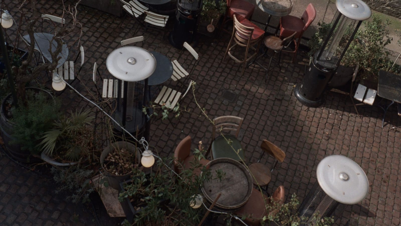 A cozy outdoor dining area with patio heaters, tables, and chairs under ambient lighting.